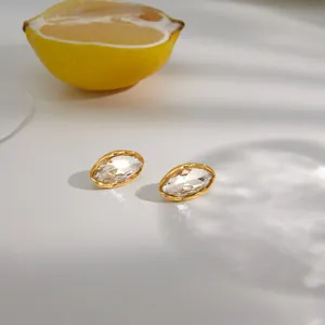 Gros plan de boucles d'oreilles dorées en titane avec cristal marquise et citron