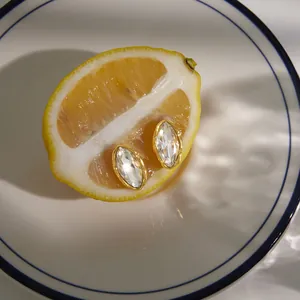 Vue détaillée de boucles d'oreilles en strass marquise sur une tranche de citron.