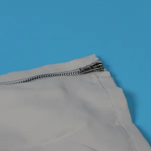 Close-up detail of a silver metal zipper on a light gray cargo skirt garment