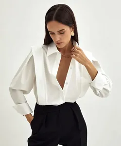 Detail view of a white cotton French shirt featuring architectural layered shoulders.