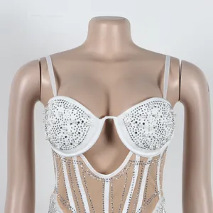 Close-up detail of luxury white bodysuit featuring intricate pearl and rhinestone patterns