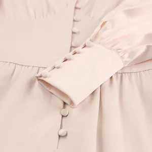Gedetailleerd overzicht van een lichtroze satijnen jurk met elegante beklede knopen en manchetten