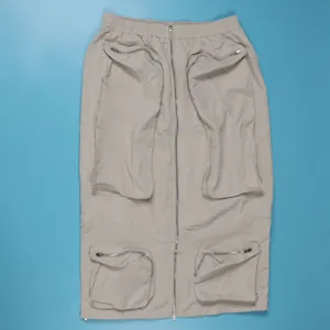 Detail view of a beige cargo skirt featuring multiple zipper pockets and a front zip