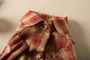 Close-up detail of a vintage red plaid pet shirt collar featuring decorative wooden buttons