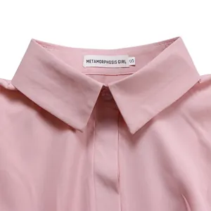 Primer plano de un cuello de camisa rosa con etiqueta de marca y tejido fino.