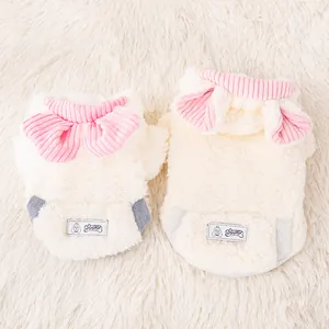 Dettaglio di felpe soffici per cani color crema con scolli a coste rosa e toppe con logo