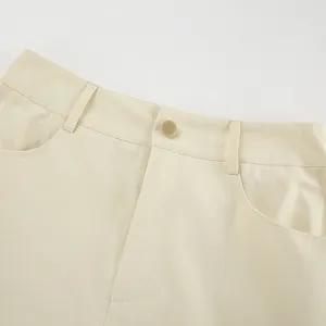 Detail view of high waist beige straight skirt showing gold button and belt loops.