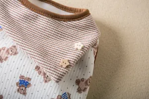Close-up of pet vest fabric featuring brown stripes, bear print, and star buttons.