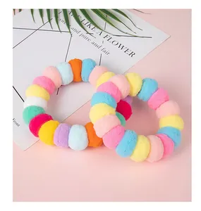 Détail d'un collier pour animaux en pompons colorés faits main sur un fond rose doux