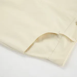 Close-up macro detail of the high waist and pocket stitching on a beige midi skirt