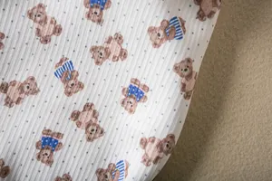 Detail view of white ribbed fabric with cute brown bear and blue dot print for pet vest.