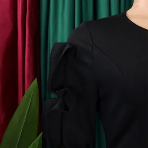 Close-up detail of ruffled shoulder design on an elegant black long sleeve dress