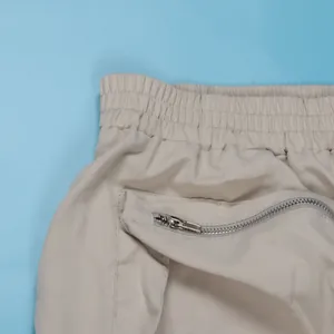 Close-up detail of beige cargo skirt with elastic waistband and functional zipper pocket.