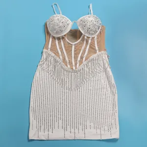 Detailed view of a white bodycon dress with sparkling rhinestones, pearls, and mesh panels.