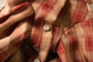 Macro view of vintage wooden button and red plaid fabric texture on a pet dog shirt