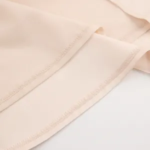 Detailopname van de nette zoomstiksels en de gladde satijnen stof van deze elegante jurk.