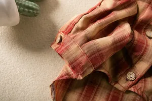 Detailed macro view showing the fabric texture and vintage button of a plaid pet shirt