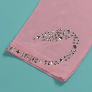 Nahaufnahme glitzernder Strassmuster auf pinkfarbenem Mesh-Stretch-Jumpsuit