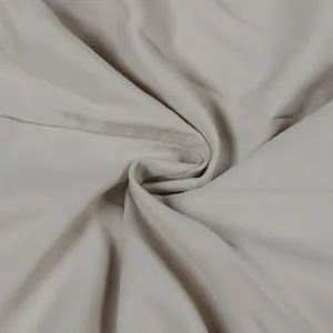 Close-up of high-quality beige workwear fabric texture showing fine weave patterns.