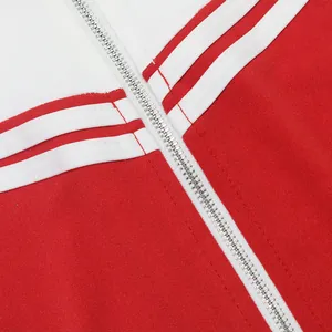 Gedetailleerde macro-opname van de metalen rits op een rood-wit sportief tweedelig trainingspak