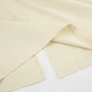 Detailed macro view of beige workwear skirt hem showing split design and stitching.