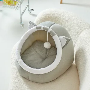 Cama para gatos gris semicerrada con orejas y bola de juego sobre un sofá