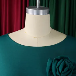 Vue détaillée de l'encolure ronde et de la fleur en tissu 3D sur cette élégante robe verte