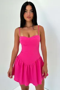 Dettaglio di un mini abito fucsia acceso con bustino a corsetto e bordo a balze.
