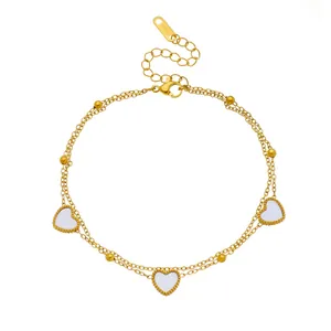 Exquisita tobillera de doble capa chapada en oro con dijes de corazón blanco y cuentas doradas.