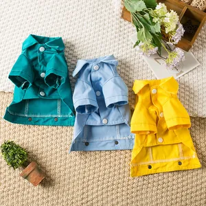 Trois chemises en denim colorées pour chiens en bleu, jaune et vert sur un tapis douillet
