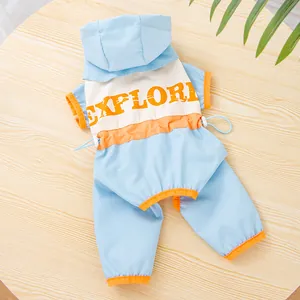 Detail of a light blue pet windbreaker with a hood and orange "EXPLORE" print on wood.