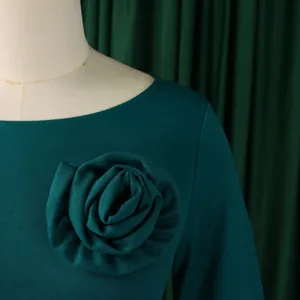 Détail d'une élégante robe vert foncé avec une grande rose en tissu faite main