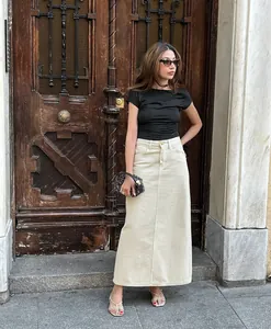 Detail view of a French style high-waisted beige straight denim skirt on a model