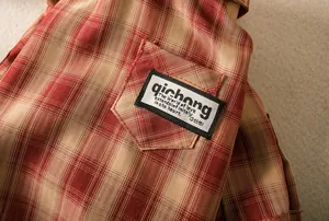 Detailed close-up of red and beige checkered pet shirt with a woven label on the pocket.