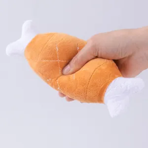 Close-up of hand squeezing a plush chicken leg pet toy showing soft and durable texture