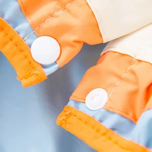 Detail view of the white snap button closure on a waterproof colorful dog raincoat