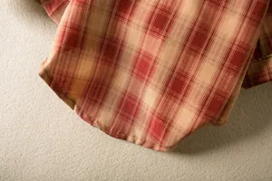 Close-up detail of plaid pet shirt fabric with high-quality stitching on curved hem