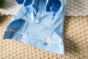 Vue rapprochée de la texture du jean bleu et du bouton-pression blanc sur la veste animal