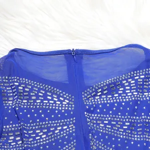 Macro view of silver rhinestone and crystal detailing on a royal blue mesh dress.