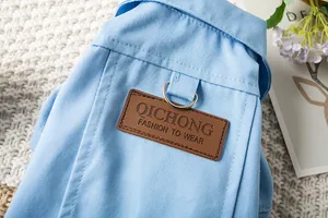 Détail en gros plan d'une veste en jean bleue pour chien avec un écusson en cuir marron.