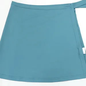 Primer plano de falda cruzada verde azulado que muestra la textura de la tela y la costura.
