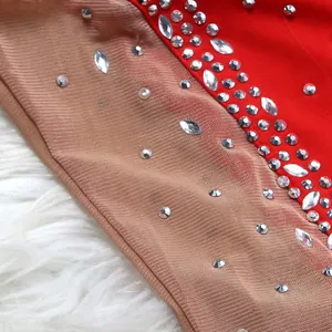 Detail view of sparkling silver rhinestones on red fabric and nude mesh dress material.