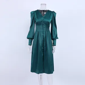 Detailweergave van een smaragdgroene satijnen midi-jurk met elegante lantaarnmouwen