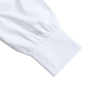 Detalle del puño de un elegante vestido camisero blanco de manga larga con pliegues