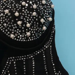 Close-up of sparkling rhinestones and white pearls on a black bodycon dress