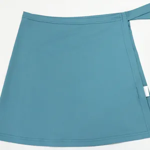 Vista detallada de una minifalda cruzada con lazada en color verde azulado y tejido suave.