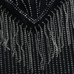 Detailed macro view of sparkling rhinestone fringe and studs on black bodycon dress