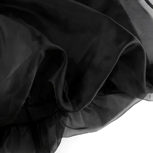 Dettaglio ravvicinato di tessuto a rete nero semitrasparente con drappeggio elegante.