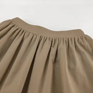 Close-up detail of khaki cotton linen A-line skirt showing pleated waistband texture
