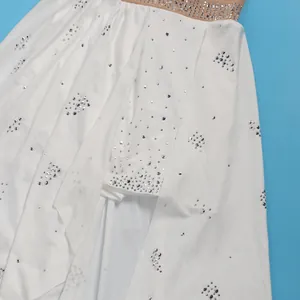 Dettaglio dei raffinati strass argentati sulla tutina bianca con orlo asimmetrico elegante